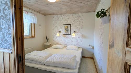 a bedroom with a bed with white sheets at Rolig häst, Kaneeling Stugby AB in Dalskog