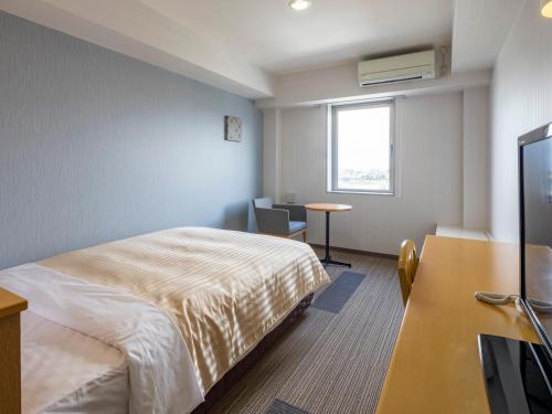 東近江市にあるコンフォートイン八日市のベッド、デスク、テレビが備わるホテルルームです。