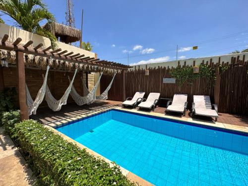 a swimming pool with lounge chairs next to a fence at Oasis Tropical in Paracuru