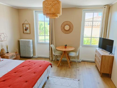 a bedroom with a bed and a table and a television at Le cottage du Breil in Verfeil