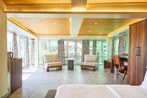 a bedroom with a desk and chairs and windows at Ruscello in Pālampur
