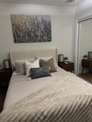 a bedroom with a large bed with a painting on the wall at Chic East LA Retreat 2 bedroom-sleeps 6-Near DTLA-Car Rental Service on Property in East Los Angeles