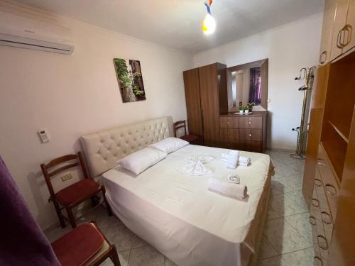 a bedroom with a white bed and a chair at Summerland Lukovë in Sarandë