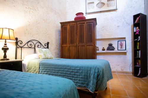 a bedroom with two beds and a wooden cabinet at Historical Green House Campeche in Campeche