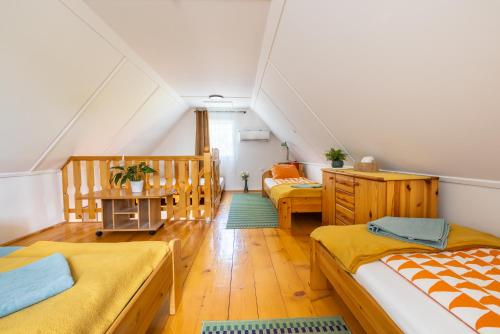 a attic room with two beds and a table at Két Fenyőfa Vendégház Vízparti Nyaraló in Békésszentandrás