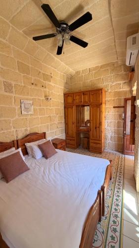a bedroom with a large bed with a ceiling fan at Stella & Stone Guesthouse in Għarb