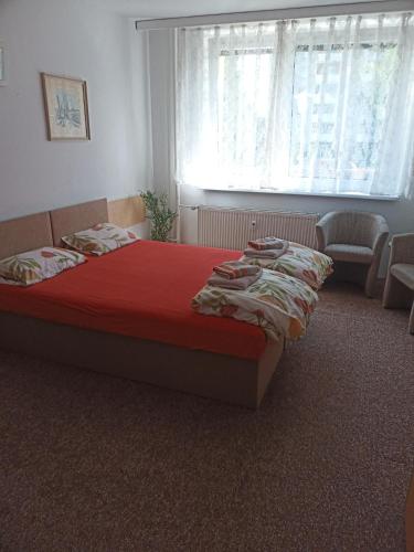 a bedroom with a bed with a red comforter and a window at Soukromé ubytování 1 in Zlín