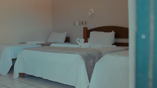 a bedroom with two beds and a table at Estância Costa do Sol in Nova Viçosa
