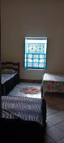 a room with three beds in front of a window at Casarão D'Ávila aluguel por temporada in Goiás