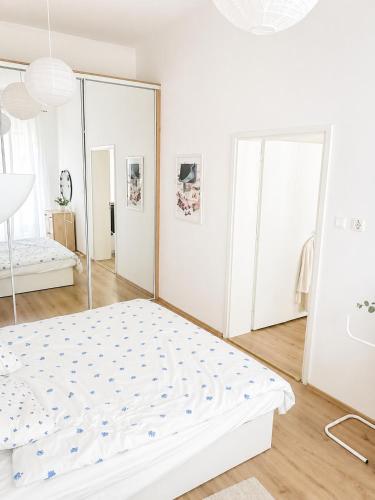 a white bedroom with a bed and a mirror at City Center Apartment in Brno