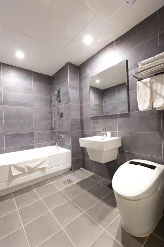 a bathroom with a toilet and a sink and a tub at Incheon Stay Hotel in Incheon