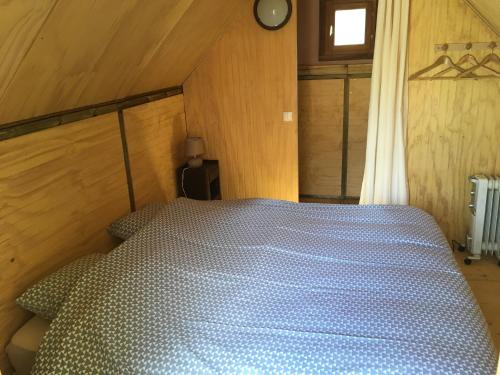 a bedroom with a bed with a blue comforter at Chalet l'écureuil in Treigny