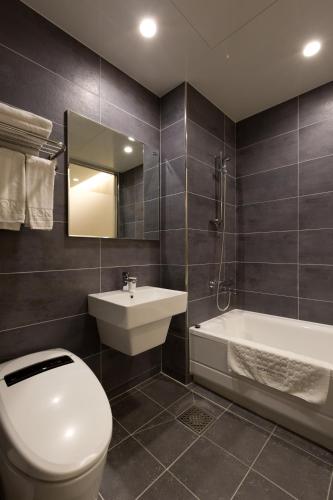 a bathroom with a toilet and a sink and a tub at Incheon Stay Hotel in Incheon