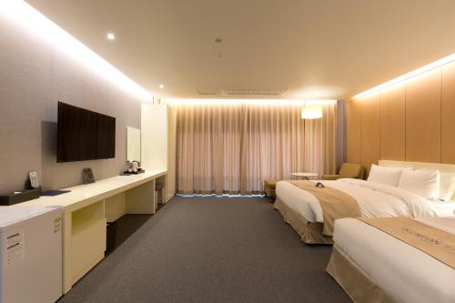 a hotel room with two beds and a flat screen tv at Incheon Stay Hotel in Incheon