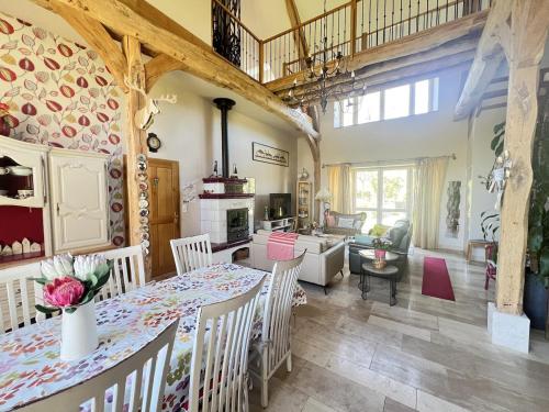 a kitchen and living room with a table and chairs at Gîte LA MELINOTHE - 12 personnes - Grand gîte de charme indépendant 5 étoiles in Paisy-Cosdon