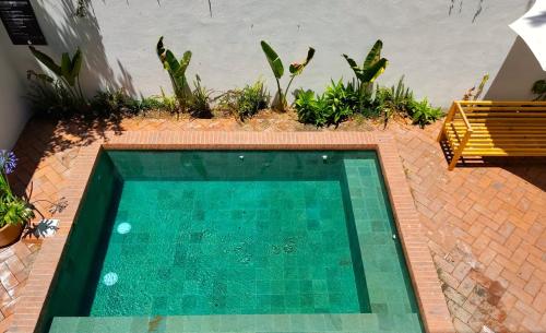 a swimming pool in a backyard with a bench and plants at Hospedarte Central Hotel in Guadalajara
