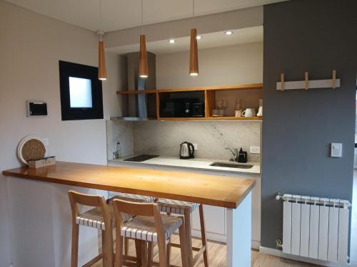 a kitchen with a wooden counter and two chairs at Panorama Aparts Chalten in El Chalten