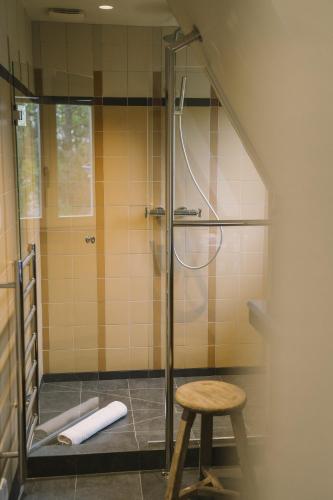 a shower stall with a stool in a bathroom at Villa Tri Men in Combrit