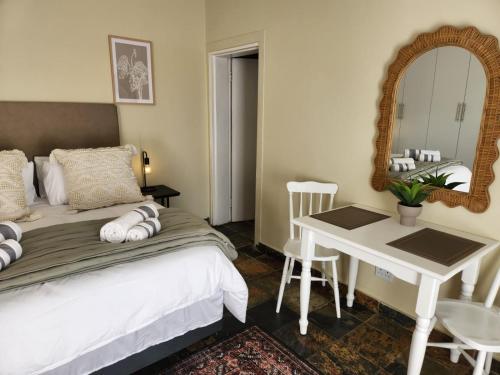 a bedroom with a bed and a table and a mirror at The Studios on Smuts in Ermelo