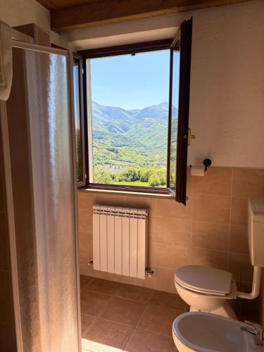 a bathroom with a toilet and a large window at Alta Quiete in Frontone
