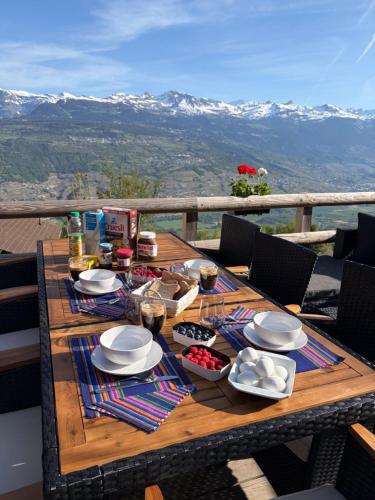 a wooden table with plates and bowls of food on it at Chalet panoramique avec vue alpine à 180 degrés - poêle scandinave & nature in Grône