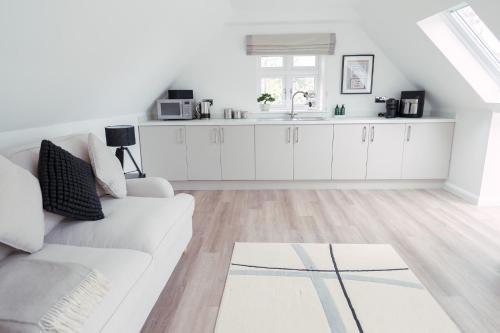 a white living room with a white couch and a kitchen at THE STUDIO - Silverstone village - walking distance to track in Silverstone