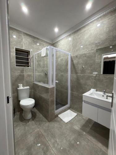 a bathroom with a shower and a toilet and a sink at Golf View Guest House in Mahikeng