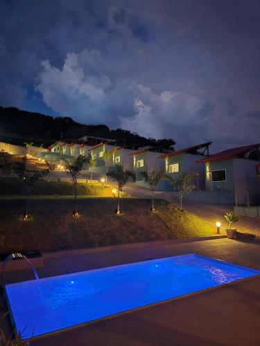 a swimming pool in front of a house at night at Pousada real chalés in Belo Vale
