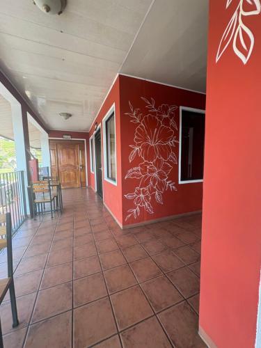 a room with a red wall and a tile floor at Aracari Stay in Quepos