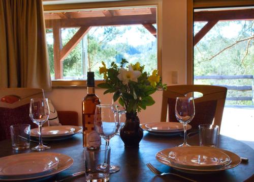 a table with glasses and a bottle of wine and flowers at Ferienhaus Siebenschläfer im Sandsteinidyll in Rathen