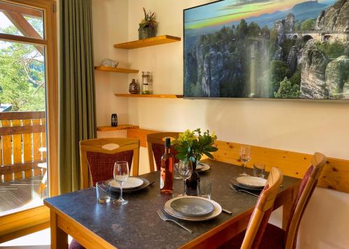 a dining table with wine glasses and a painting on the wall at Ferienwohnung Villa Oben im Sandsteinidyll in Rathen