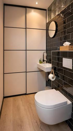 a bathroom with a white toilet and a sink at Buddelhuus in Norddeich