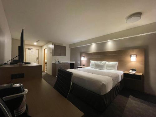 a hotel room with a large bed and a kitchen at Chalet Continental Motel in Valemount