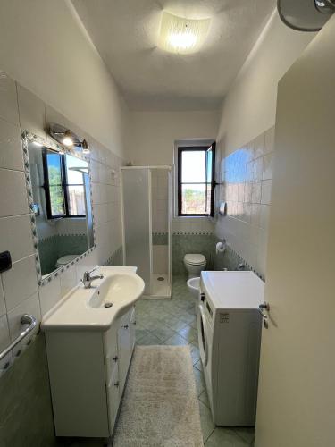 a white bathroom with a sink and a toilet at Il Quinto senso di Lù in Capalbio