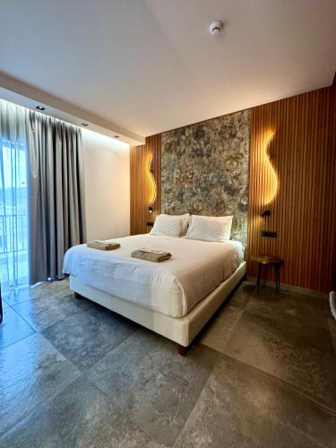 a bedroom with a large bed and a stone wall at IONIAN SUITES by Bruskos in Agios Georgios
