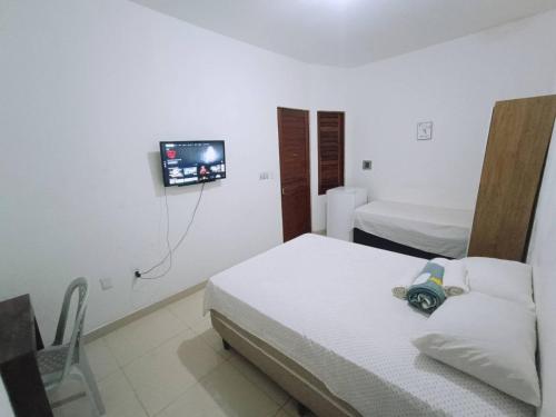 a bedroom with two beds and a tv on the wall at Pousada Maria Bonita - Centro, 10min da Praia de Camapum, Macau RN in Macau