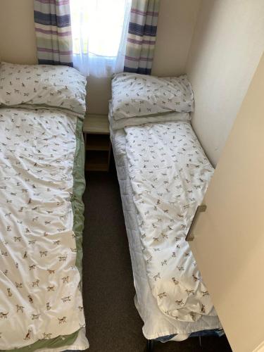 two beds in a small room with a window at Faville in Selsey