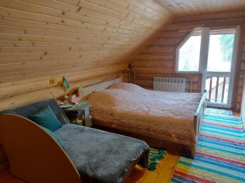 a bedroom with a bed and a couch in a log cabin at У Медовому Раю in Rostoka