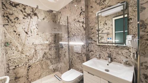 a bathroom with a sink and a toilet and a mirror at Hotel Ruko Boutique Deluxe in Golem