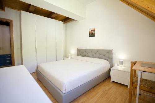 a white bedroom with a bed and a table at Casa Azzurra - Spacious apartment in the heart of Julian Alps in Cave del Predil