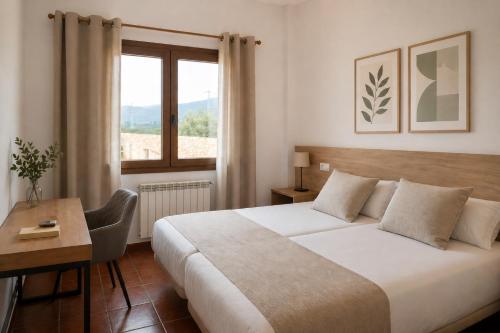 a bedroom with a bed and a desk and a window at L'Albea Hotel Rural in Vall dʼAlba