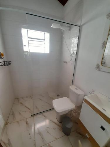 a white bathroom with a toilet and a sink at Recanto do Gigante Adormecido in Joanópolis