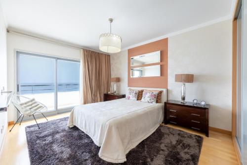 a bedroom with a large bed and a large window at Sesimbra Mar Apartamento in Sesimbra