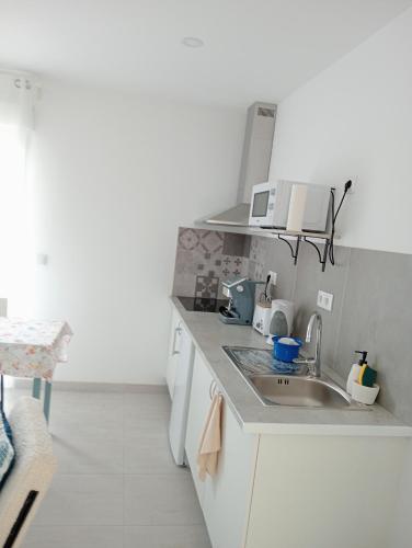 a white kitchen with a sink and a microwave at Casa Coruja in Ponte da Barca