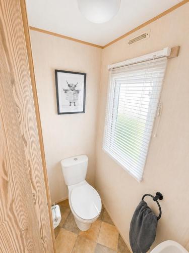 a bathroom with a toilet and a window at Golden Sands Getaways Weymouth in Wyke Regis