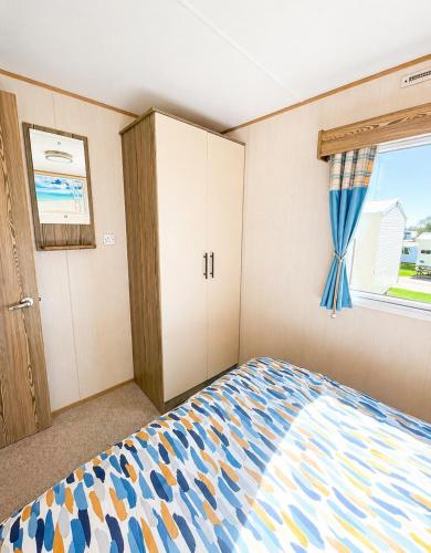 a bedroom with a bed and a window at Golden Sands Getaways Weymouth in Wyke Regis