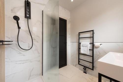a white bathroom with a shower and a sink at Murray Cottage in Gardenstown