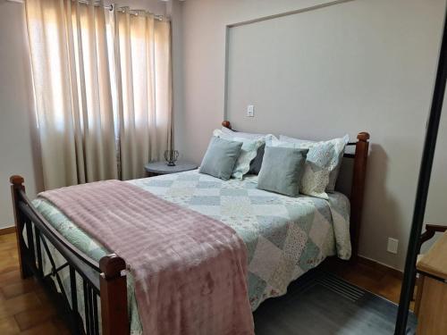 a bedroom with a bed with a blanket and pillows at Studio chamorso - Cama Queen - AC - Garagem in Rondonópolis