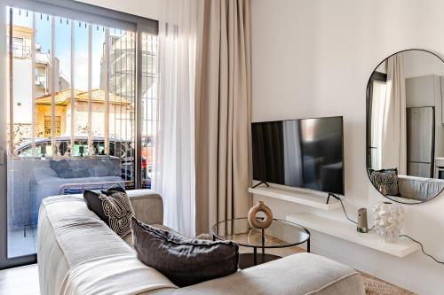 a living room with a couch and a large window at Yamas Urban Living Olympia Suites Old Town Studio in Limassol