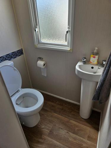 a bathroom with a toilet and a sink and a window at PMH rental in Saint Osyth